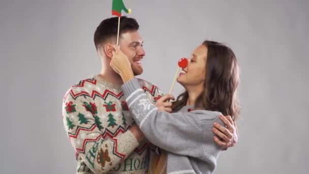 Pareja con accesorios de fiesta de Navidad en cabina de fotos — Vídeos de Stock