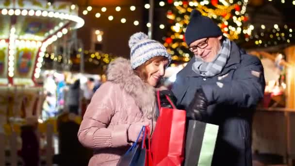 Casal velho no mercado de natal com sacos de compras — Vídeo de Stock