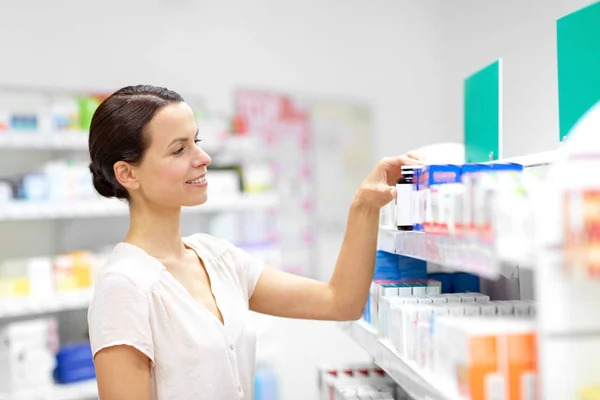 Cliente femenino eligiendo medicamentos en la farmacia —  Fotos de Stock