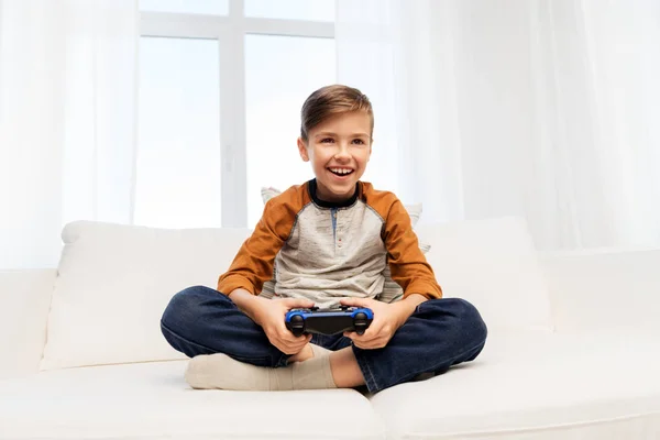 Χαρούμενο αγόρι με gamepad που παίζει βιντεοπαιχνίδι στο σπίτι — Φωτογραφία Αρχείου