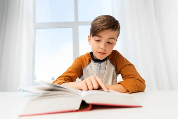 Student boy reading book at home table — Stock Photo, Image