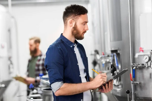 Hombre con portapapeles en cervecería artesanal o fábrica de cerveza —  Fotos de Stock