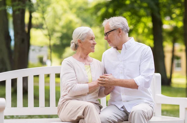 Glada äldre par sitter på bänk i parken — Stockfoto