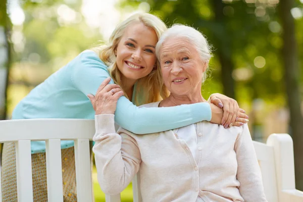 Fille avec mère aînée étreignant sur le banc du parc — Photo