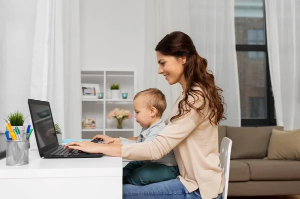 Madre felice con bambino e laptop che lavorano a casa — Foto Stock