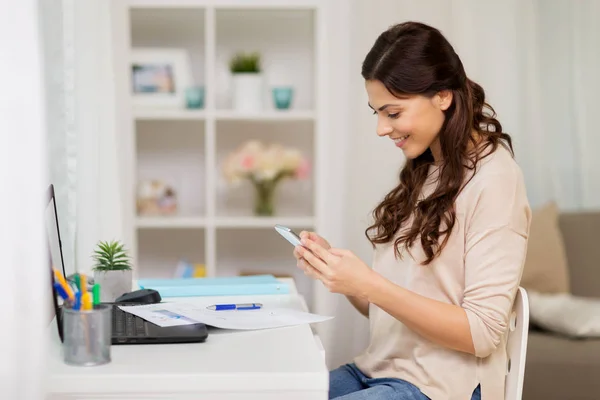 Vrouw met papieren en smartphone thuis werken — Stockfoto