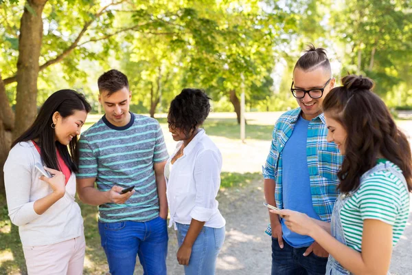 Gelukkige vrienden met smartphones bij zomer park — Stockfoto