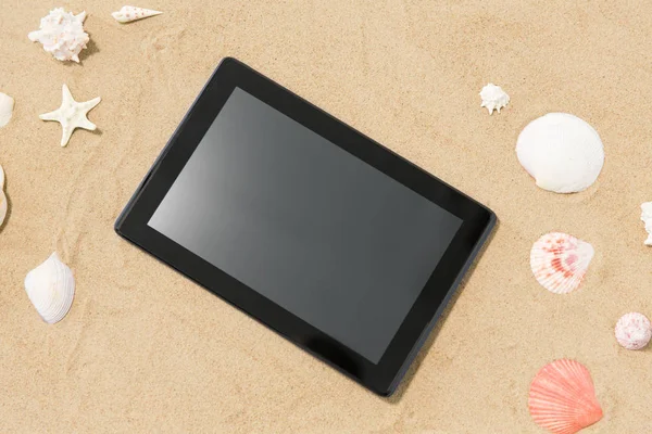 Tablet computador e conchas na areia da praia — Fotografia de Stock