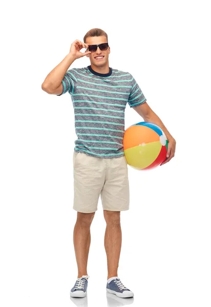 Joven sonriente en gafas de sol con pelota de playa — Foto de Stock