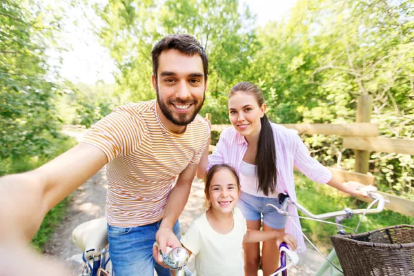 Familia feliz con bicicletas tomando selfie en verano —  Fotos de Stock