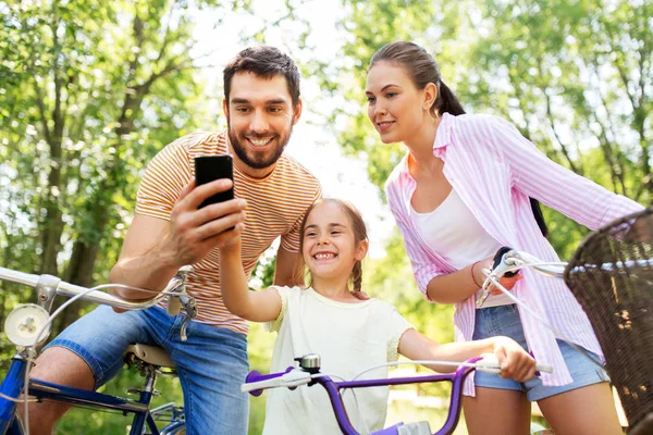 Familie mit Smartphone und Fahrrädern im Sommerpark — Stockfoto