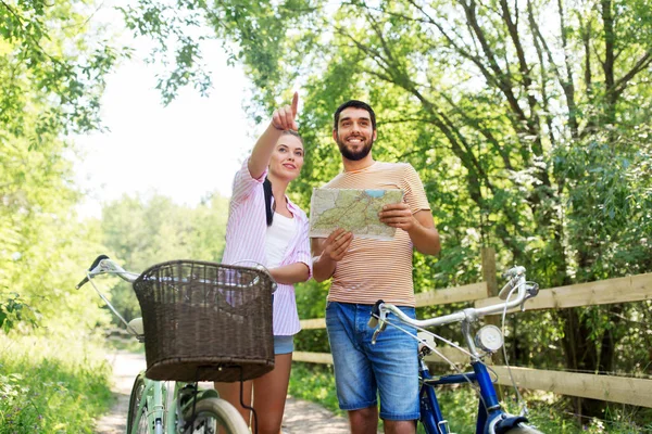 Пара с картой и велосипедами в стране летом — стоковое фото