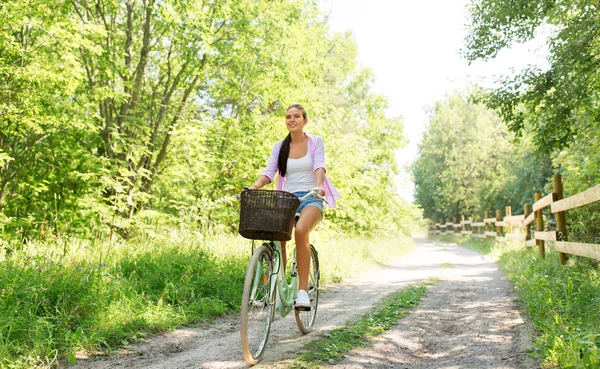 Kobieta jazdy na rowerze z koszem na lato park — Zdjęcie stockowe