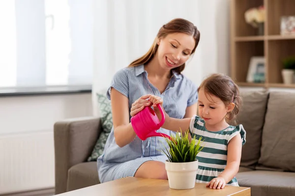 Pregnant mother and daughter watering home plant — Stock Photo, Image