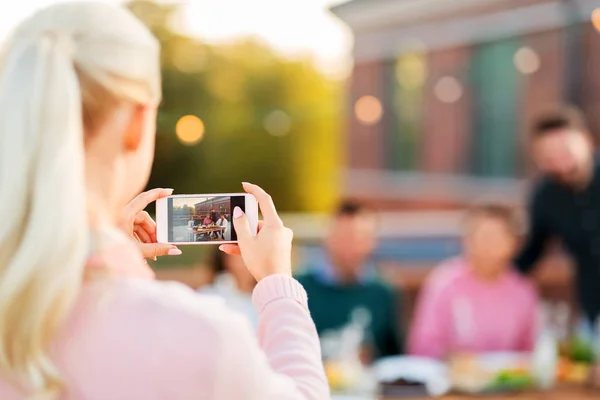 Frau fotografiert Freunde auf Party mit dem Smartphone — Stockfoto