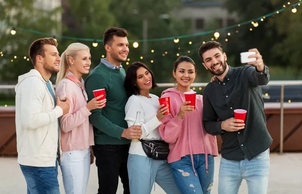 Vrienden met dranken selfie nemen op dak feestje — Stockfoto