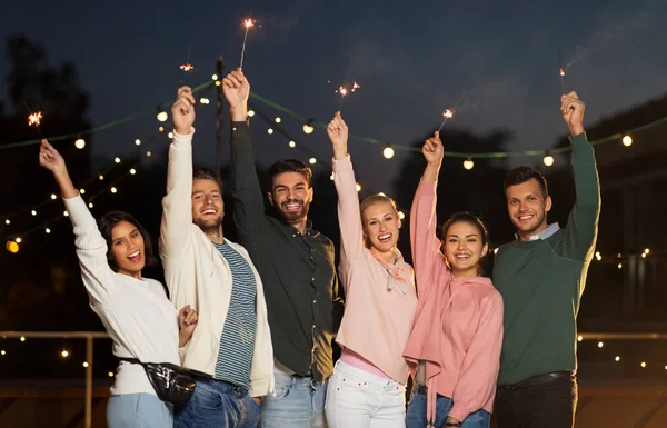 Amigos felices con bengalas en la fiesta en la azotea — Foto de Stock