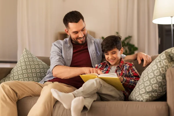 Lycklig far och son läser bok soffa hemma — Stockfoto