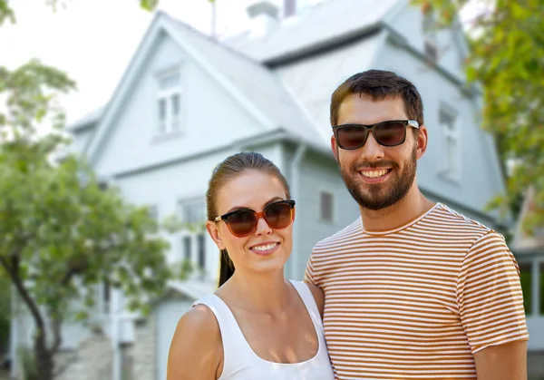 Feliz pareja en gafas de sol en verano sobre casa —  Fotos de Stock