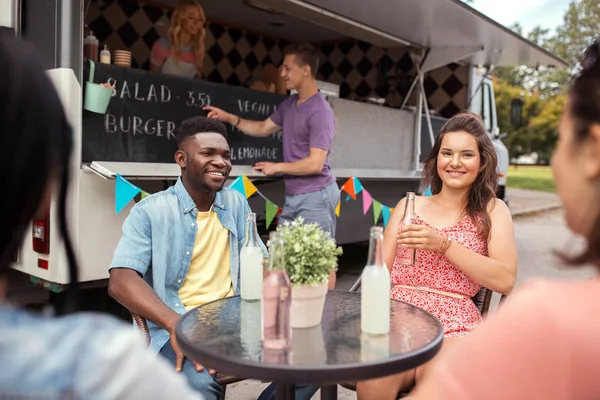 Amis avec des boissons assis à table au camion de nourriture — Photo