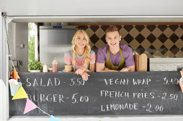 Couple de jeunes vendeurs heureux au camion de nourriture — Photo