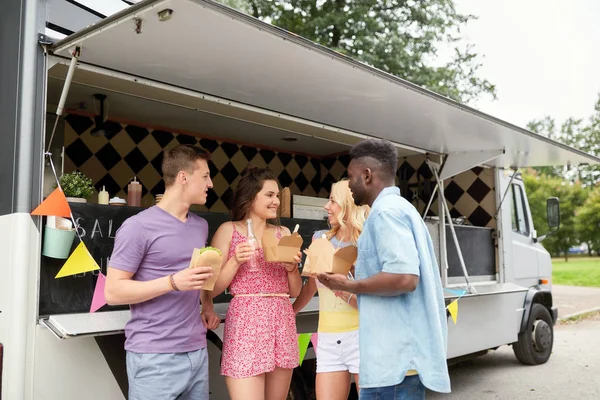 Amigos felices con bebidas comiendo en camión de comida — Foto de Stock