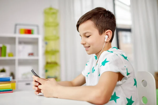 Garçon dans les écouteurs écouter de la musique sur smartphone — Photo