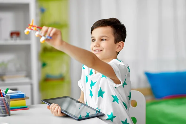 Мальчик с планшетным компьютером и игрушечным самолетом дома — стоковое фото