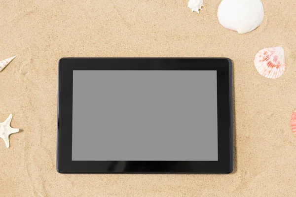Tablet computador e conchas na areia da praia — Fotografia de Stock