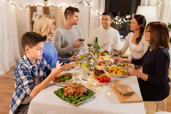 Ragazzo con smartphone alla cena in famiglia — Foto Stock