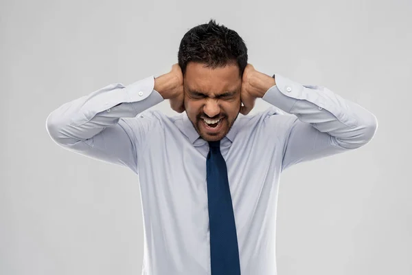Homem de negócios gritando cobrindo ouvidos com as mãos — Fotografia de Stock