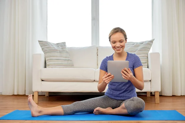 Mujer con tablet ordenador haciendo yoga en casa — Foto de Stock