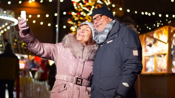 Pareja de ancianos tomando selfie en el mercado de Navidad — Vídeos de Stock