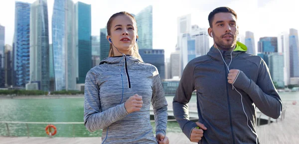 Pareja con auriculares corriendo sobre singapore — Foto de Stock