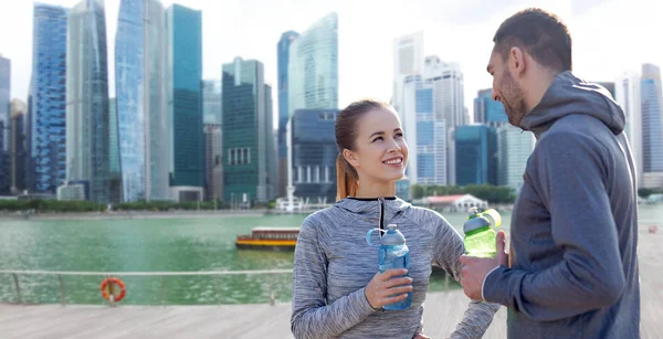 Pareja con botellas de agua sobre la ciudad de Singapur — Foto de Stock