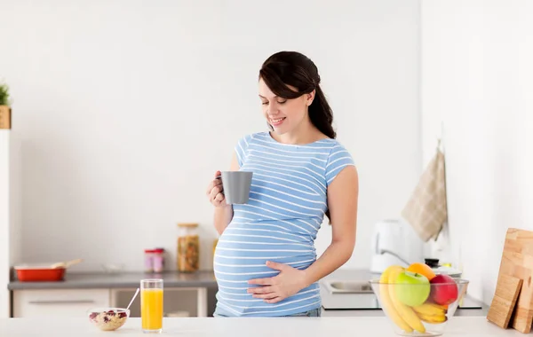 Happy pregnant woman with cup at home kitchen — Stock Photo, Image