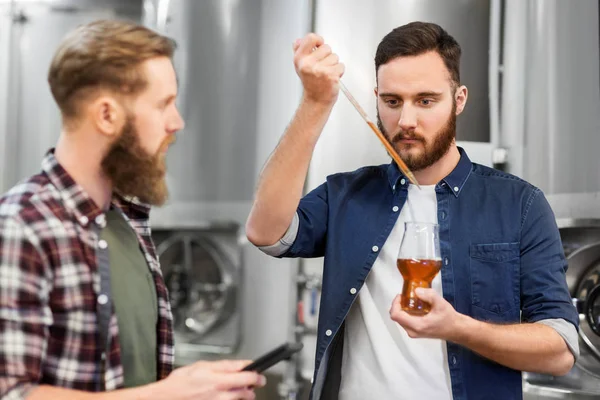 Muži s pipetou testují řemeslné pivo v pivovaru — Stock fotografie