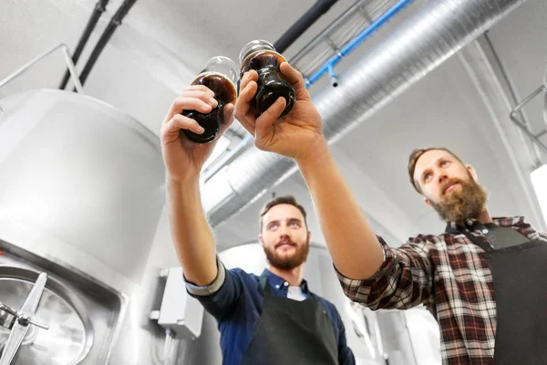 Brewers cinkání sklenic řemeslo piva v pivovaru — Stock fotografie