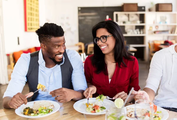 Happy friends eating and talking at restaurant — Stock Photo, Image