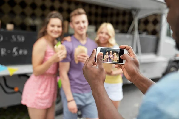 Homem tirando foto de amigos comendo no caminhão de comida — Fotografia de Stock