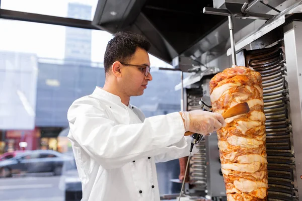 Chef rebanando carne doner de escupir en la tienda de kebab —  Fotos de Stock