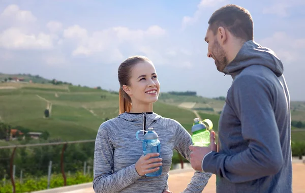 Pareja con botellas de agua después de los deportes al aire libre — Foto de Stock