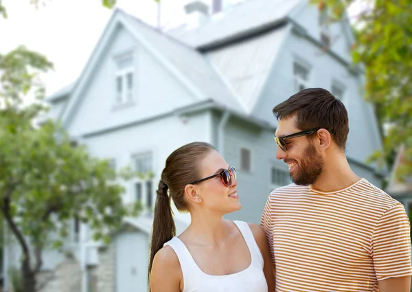 Happy couple in sunglasses in summer over house — Stock Photo, Image