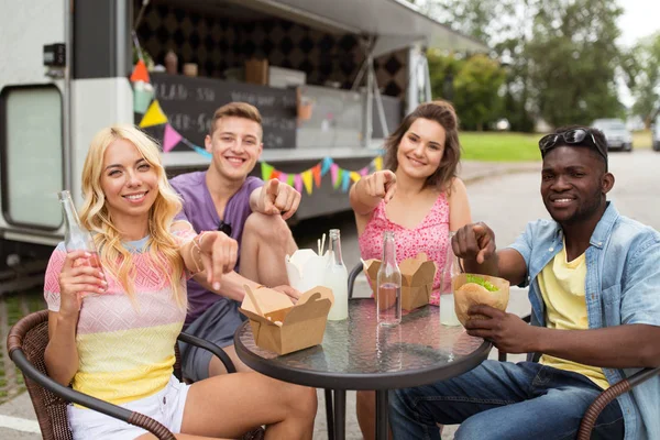 Glada vänner med drycker som äter på foodtruck — Stockfoto