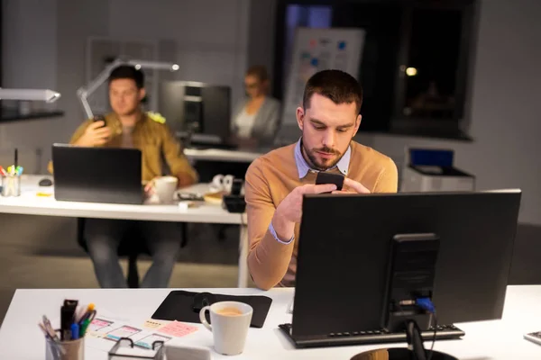 Hombre con smartphone trabajando hasta tarde en la oficina nocturna —  Fotos de Stock