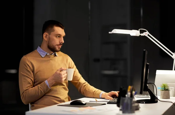 Mann mit Laptop und Kaffee arbeitet nachts im Büro — Stockfoto