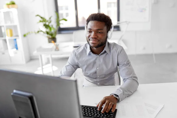 Homem de negócios com fones de ouvido e computador no escritório — Fotografia de Stock