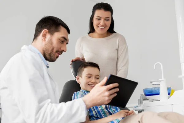 Dentista mostrando tableta PC a niño en la clínica dental —  Fotos de Stock