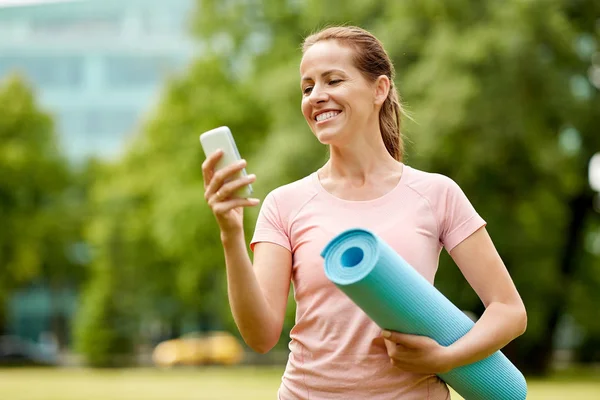 Vrouw met Trainingsmat en smartphone bij park — Stockfoto