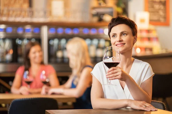 Mujer feliz bebiendo vino tinto en el bar o restaurante — Foto de Stock